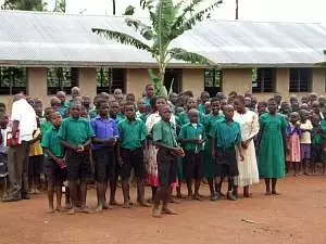 Children, many of them in green shirts and dresses, line up outside Mugungulu School